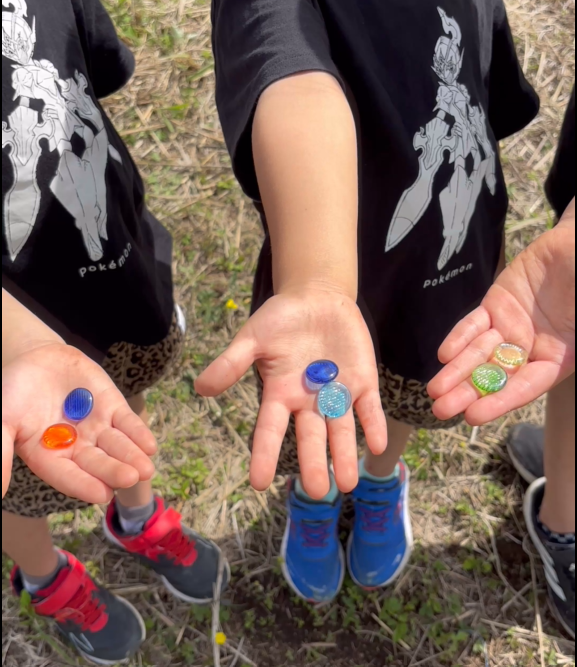 宝探しで見つけたビー玉を持つ子ども